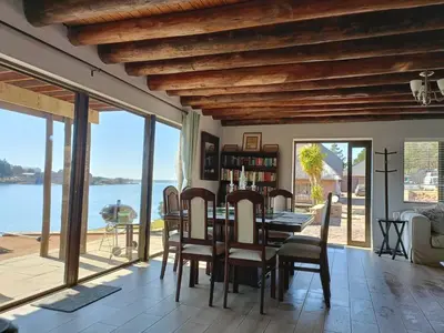 a dining room with a table and views of the water at Sedgefield Lodge in Witbank