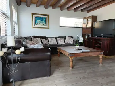 a living room with a leather couch and a coffee table at Sedgefield Lodge in Witbank