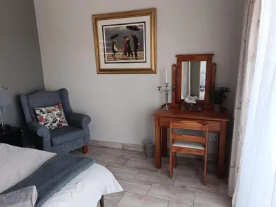 a bedroom with a desk and a chair and a mirror at Sedgefield Lodge in Witbank