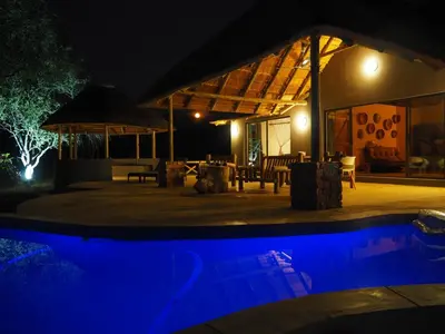 a night view of a house with a swimming pool at Pata Pata House in Marloth Park
