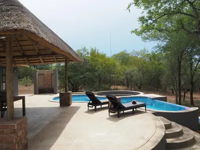 a patio with two chairs and a swimming pool at Pata Pata House in Marloth Park
