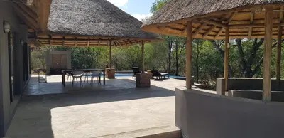 a patio with a table and chairs and umbrellas at Pata Pata House in Marloth Park