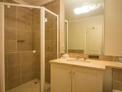 a bathroom with a shower and a sink and a mirror at Bellstone B&B in Pretoria
