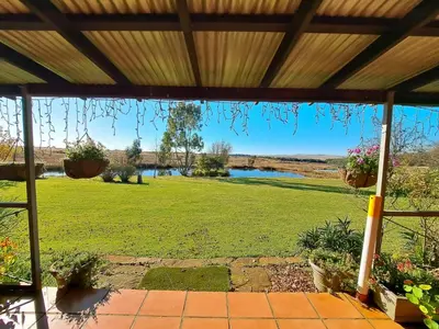 a view from the porch of a house with a lawn and a river at Dullstroom Manor Game & Trout Lodge in Dullstroom
