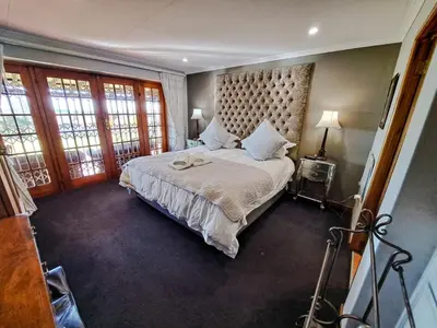 a bedroom with a large bed with a large headboard at Dullstroom Manor Game & Trout Lodge in Dullstroom