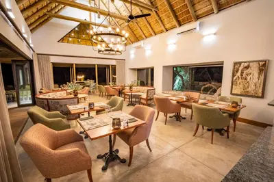 a dining room with tables and chairs and windows at Simbavati Camp George in Klaserie Private Nature Reserve