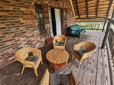 a patio with wicker chairs and a table and chairs at Athule Inn Marloth - House in Marloth Park