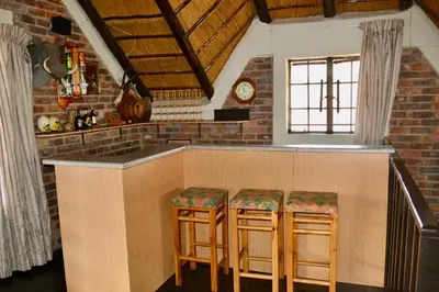 a kitchen with a bar with stools in a room at Athule Inn Marloth - House in Marloth Park