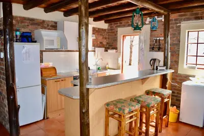a kitchen with a counter and some stools in it at Athule Inn Marloth - House in Marloth Park