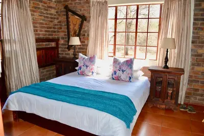 a bedroom with a white bed with pillows on it at Athule Inn Marloth - House in Marloth Park