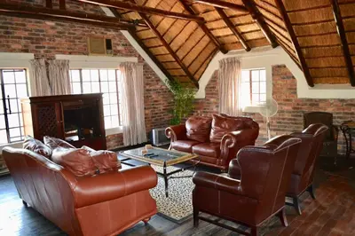 a living room with leather furniture and a brick wall at Athule Inn Marloth - House in Marloth Park