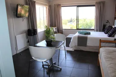a hotel room with two beds and a chair and a tv at 94onWild in Pretoria