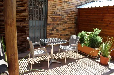 a patio with a table and chairs and a fence at 94onWild in Pretoria