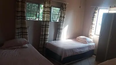 a bedroom with two beds and two windows at Confortable farmhouse in Limpopo Province in Lephalale
