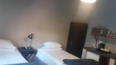 a room with two beds and a desk with a lamp at Confortable farmhouse in Limpopo Province in Lephalale