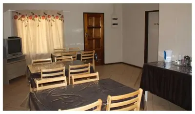 a dining room with a table and chairs and a television at Homely room in peaceful and comfortable old farmhouse in Lephalale