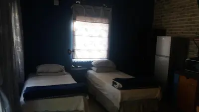 two twin beds in a room with a window at Homely room in peaceful and comfortable old farmhouse in Lephalale