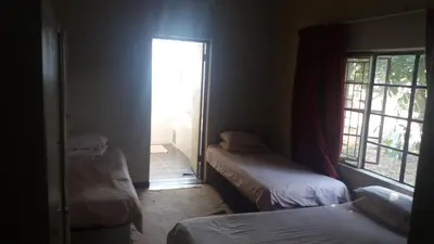 a room with two beds and a door to a window at Comfy room with dstv and aircon in convenient location in Lephalale