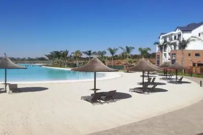 a pool with chairs and umbrellas on a beach at The Blyde - Little Place, Lots of Relaxation in Pretoria