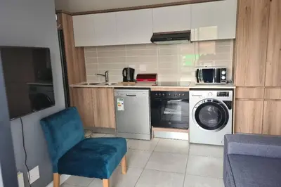 a kitchen with a washing machine and a blue chair at The Blyde - Little Place, Lots of Relaxation in Pretoria