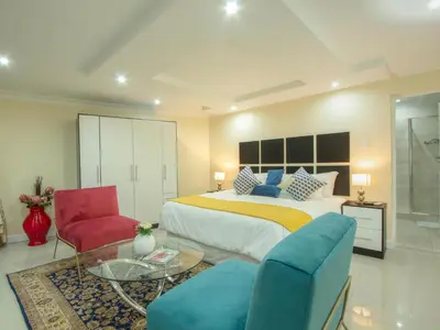 a bedroom with a bed and two chairs and a table at Royal Hills Lodge and Spa in Thohoyandou