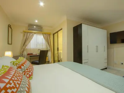 a bedroom with a large white bed and a desk at Royal Hills Lodge and Spa in Thohoyandou