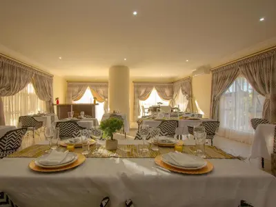 a dining room with a white table with plates and glasses at Royal Hills Lodge and Spa in Thohoyandou