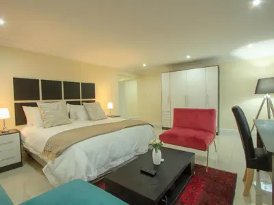 a bedroom with a large bed and a red chair at Royal Hills Lodge and Spa in Thohoyandou