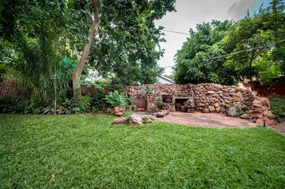 a stone building in a yard with a grass field at Interlude Guest House in Thabazimbi