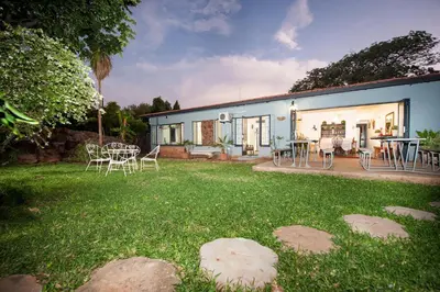 a house with a yard with chairs and a table at Interlude Guest House in Thabazimbi