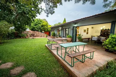 a patio with two tables and benches in a yard at Interlude Guest House in Thabazimbi