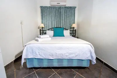 a bedroom with a large bed with blue pillows at Interlude Guest House in Thabazimbi