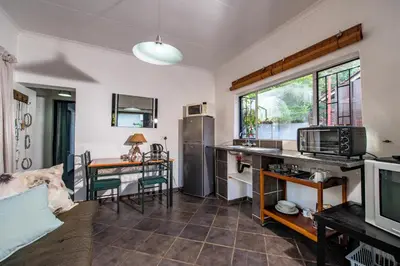 a living room with a kitchen and a table at Interlude Guest House in Thabazimbi