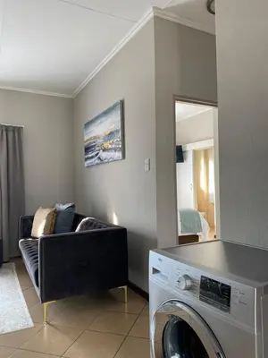a living room with a washing machine and a couch at Spring Acres Apartment living in Nelspruit