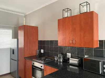 a kitchen with black counter tops and wooden cabinets at Spring Acres Apartment living in Nelspruit