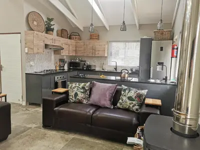 a living room with a leather couch in a kitchen at SiriMiri Cottage Dullstroom in Dullstroom