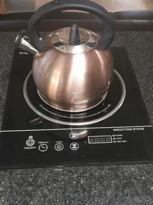 a metal tea pot sitting on a stove at SiriMiri Cottage Dullstroom in Dullstroom