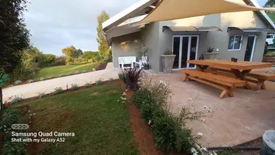 a picnic table and a bench in front of a house at SiriMiri Cottage Dullstroom in Dullstroom