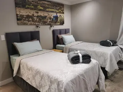 a room with two beds and a chair at SiriMiri Cottage Dullstroom in Dullstroom