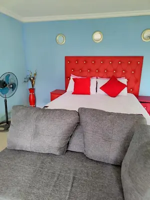 a bedroom with a large bed with red pillows at Moholoholo Lodge in Acornhoek