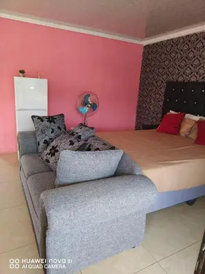 a bedroom with a bed and a couch next to a couch at Moholoholo Lodge in Acornhoek