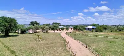 a field with houses and a dirt road at Moholoholo Lodge in Acornhoek