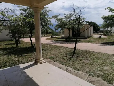 a porch with a column in a yard with trees at Moholoholo Lodge in Acornhoek