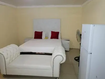 a bedroom with a white bed and a white chair at Moholoholo Lodge in Acornhoek