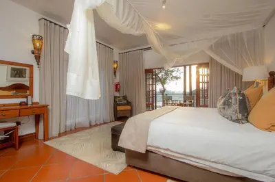 a bedroom with a bed and a desk and a window at Kruger Private Lodge in Marloth Park