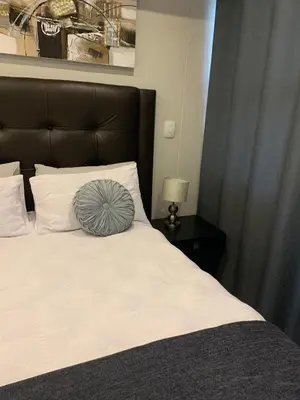 a bed with a blue pillow on top of it at Regency Hotel Apartment @ 4th in Pretoria