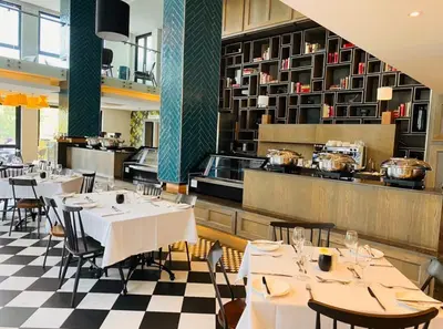 a restaurant with white tables and chairs and a kitchen at Regency Hotel Apartment @ 4th in Pretoria