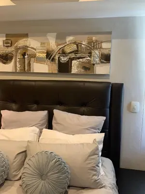 a bed with a black headboard and white pillows at Regency Hotel Apartment @ 4th in Pretoria