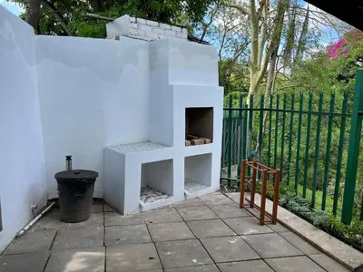 a white brick oven sitting next to a fence at Sister's Haven in Nelspruit