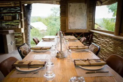 a long wooden table in a restaurant with chairs at Bundox Explorer Camp in Hoedspruit